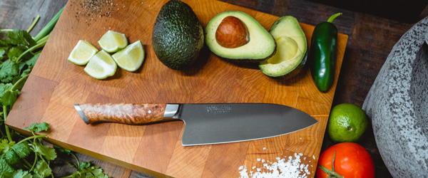 6-inch carbon steel chef knife on a cutting board surrounded by vegetables