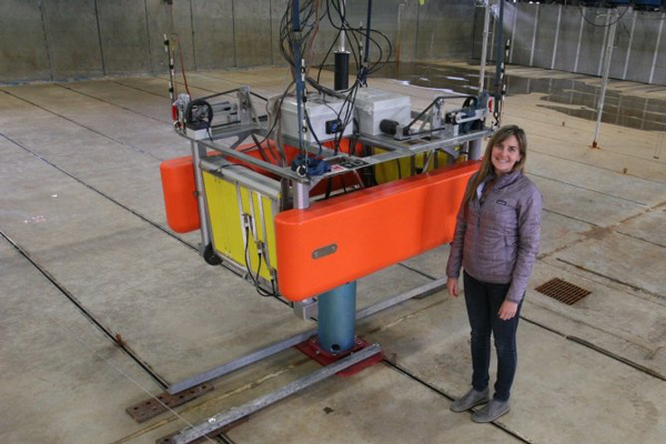 Kelley Ruehl standing next to an ocean wave energy converter.